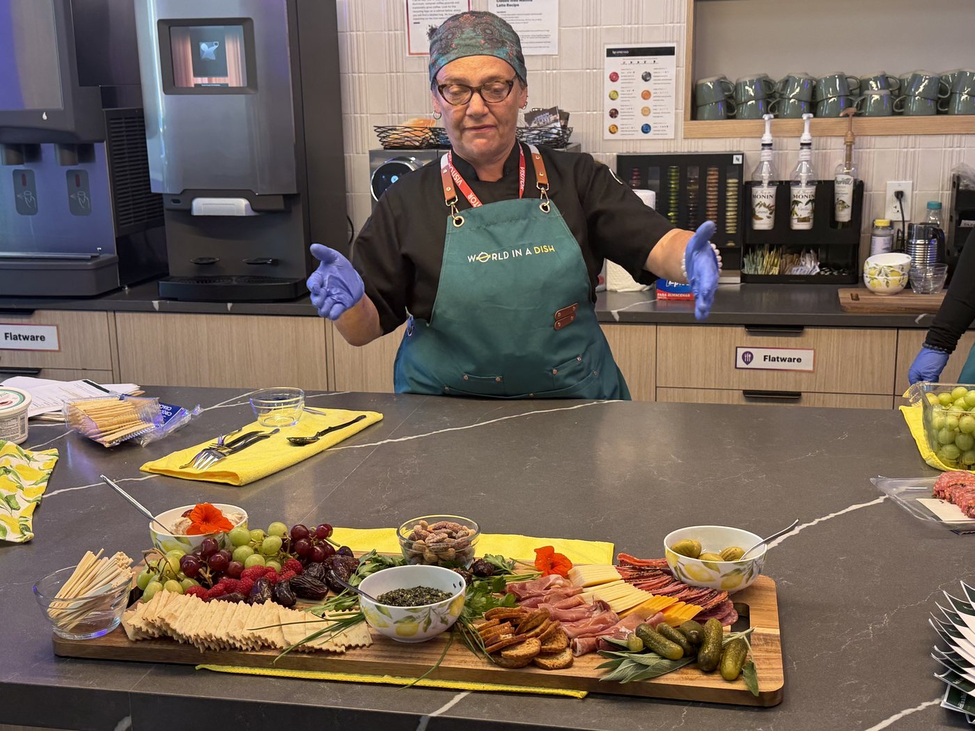 A World in a Dish chef presenting a grazing board of cured meats, cheeses, fruit, nuts and olives at an off-site team event